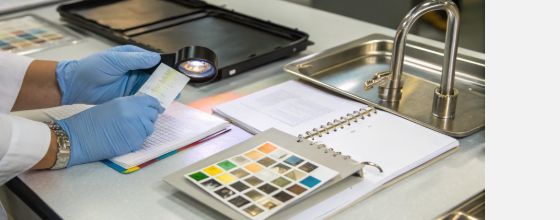 Supplier qualification audit inspecting holographic film swatch under loupe